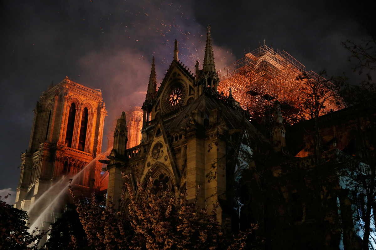 Sparks fill the air as Paris Fire brigade members spray water to extinguish flames as the Notre Dame Cathedral burns in Paris, France, April 15, 2019. REUTERS/Philippe Wojazer