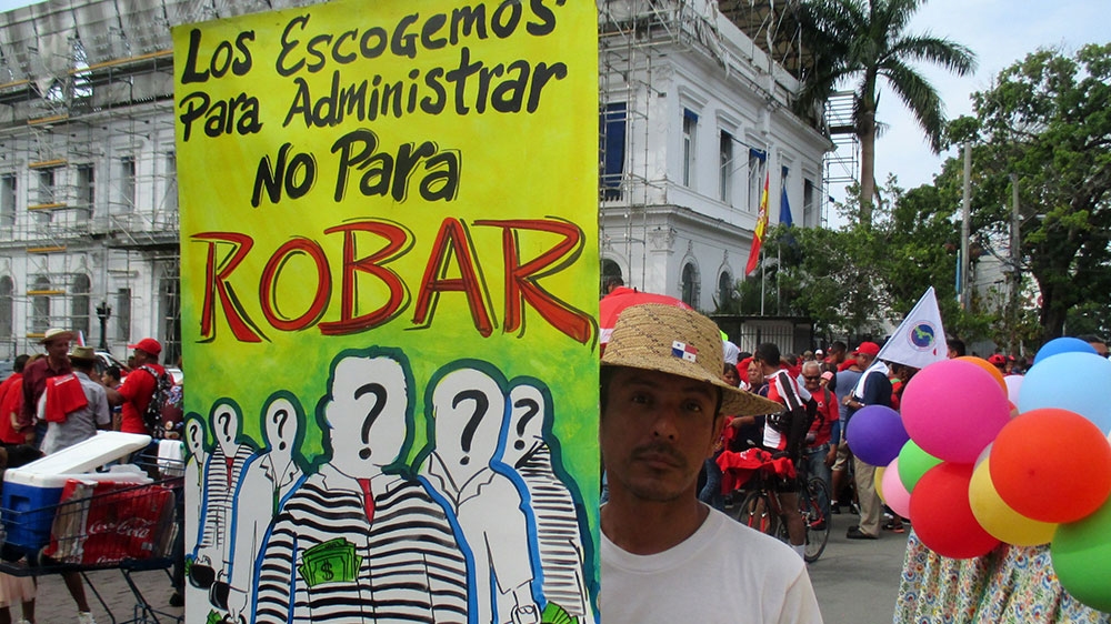 A man holds a sign that reads, 'We choose them to manage, not to steal' [Sandra Cuffe/Al Jazeera]