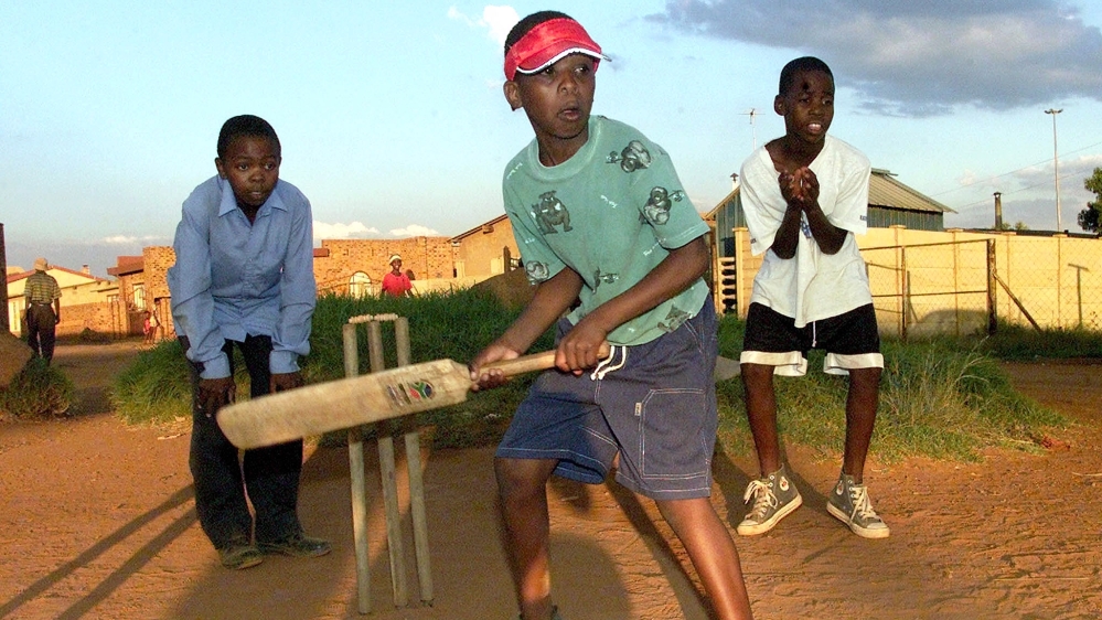 Lesego Chauke waits for the ball as he bats in front of wicketkeeper Tebogo Mashila and fielder Buti Phadima, as they play cricket after school in one of the black township in Tsakane Brakpan, east of