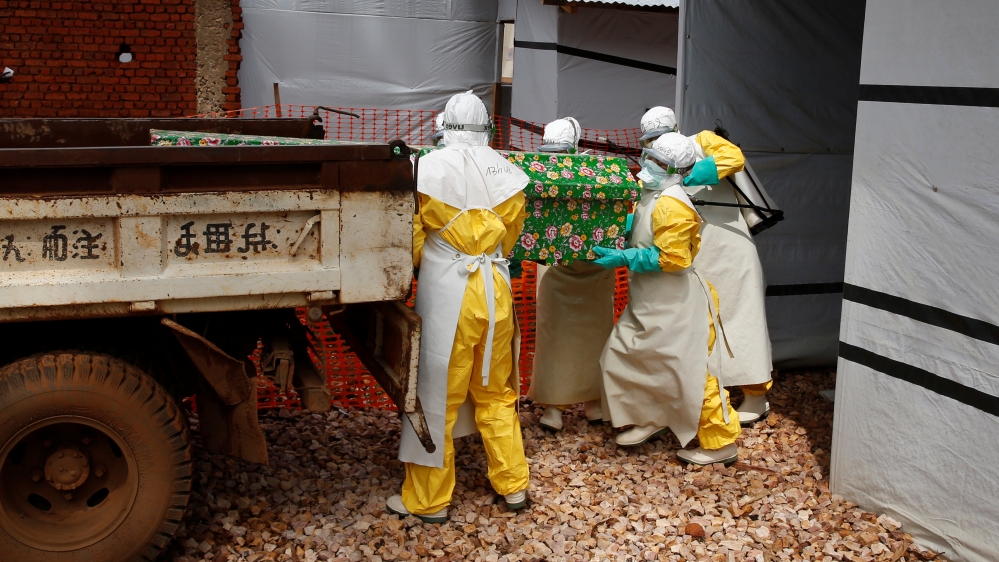 Health workers dressed in Ebola protective suits place a coffin containing the body of an Ebola patient to a truck at an Ebola treatment centre in Butembo