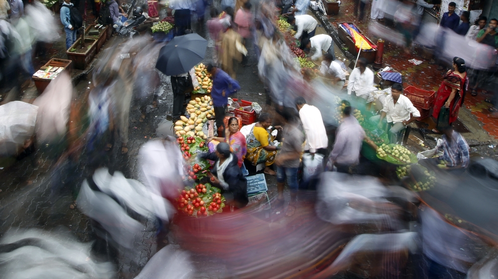Indians walk past a market area near a train station on World Population Day in Mumbai, India, Thursday, July 11, 2013