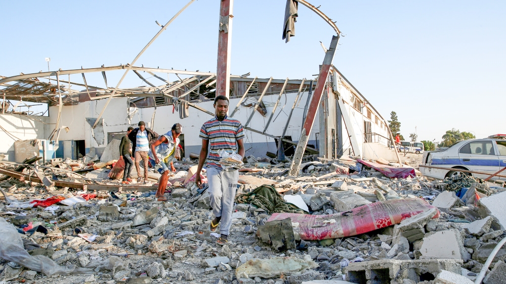 Migrants carry the remains of their belongings from among rubble at a detention centre for mainly African migrants that was hit by an airstrike in the Tajoura suburb of the Libyan capital of Tripoli,