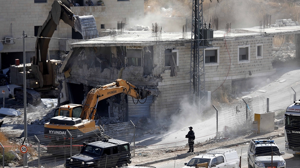 An Israeli army bulldozer demolishes a building in the Palestinian village of Sur Baher, in East Jerusalem, 22 July 2019. Israeli authorities decided to demolish at least six Palestinian residential b