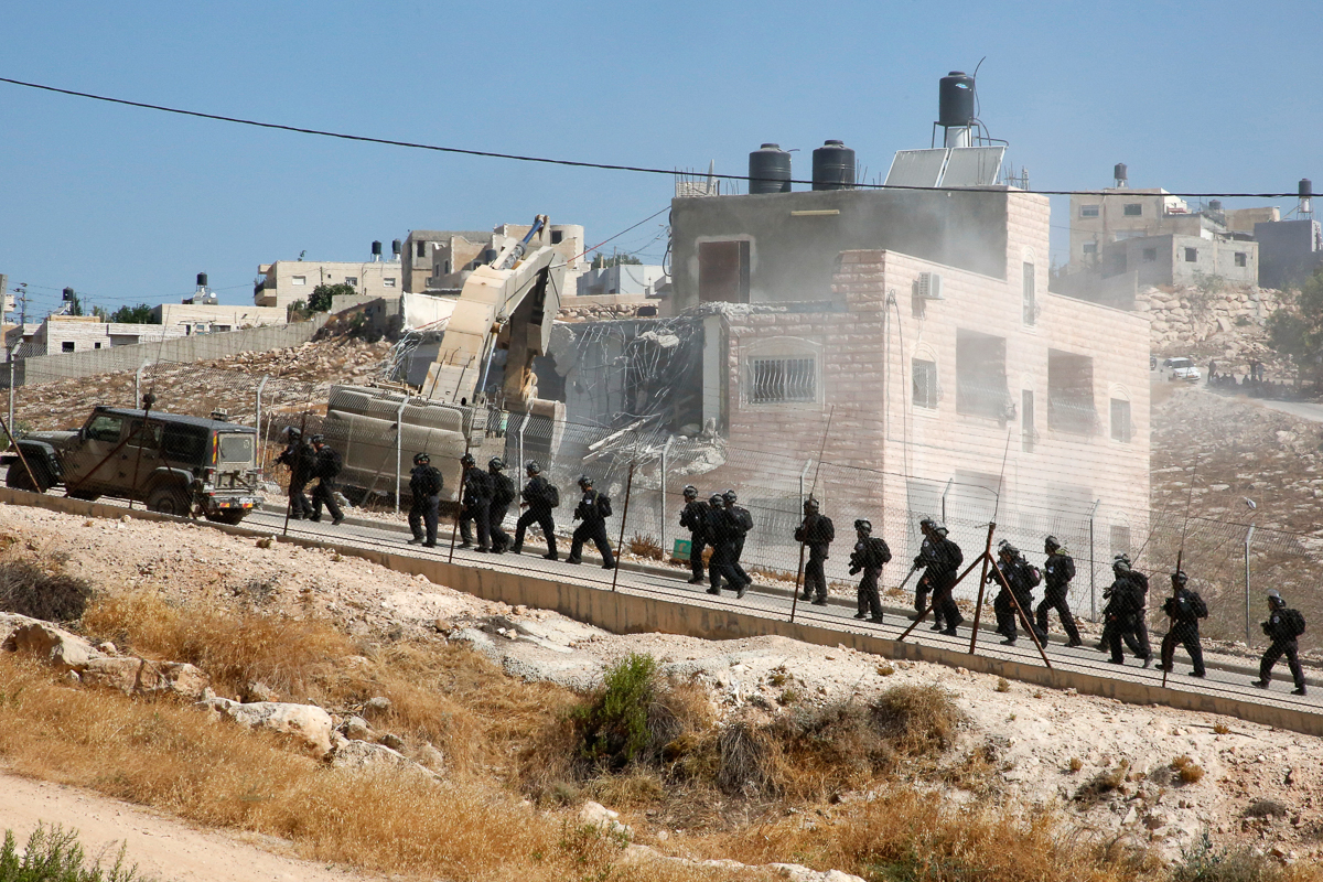 This picture taken from the West Bank on July 22, 2019 shows Israeli security forces tearing down one of the Palestinian buildings still under construction which have been issued notices to be demolis