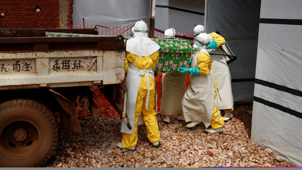 Health workers dressed in Ebola protective suits place a coffin containing the body of an Ebola patient to a truck at an Ebola treatment centre in Butembo