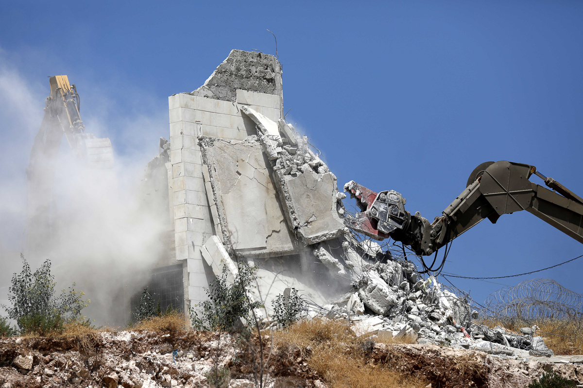 An Israeli army excavator machine demolishes a building in the Palestinian village of Sur Baher, in East Jerusalem, 22 July 2019. Israeli authorities decided to demolish at least six Palestinian resid