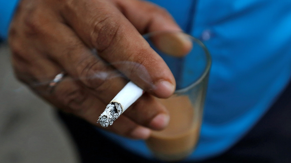 A man smokes a cigarette along a road in Mumbai, India