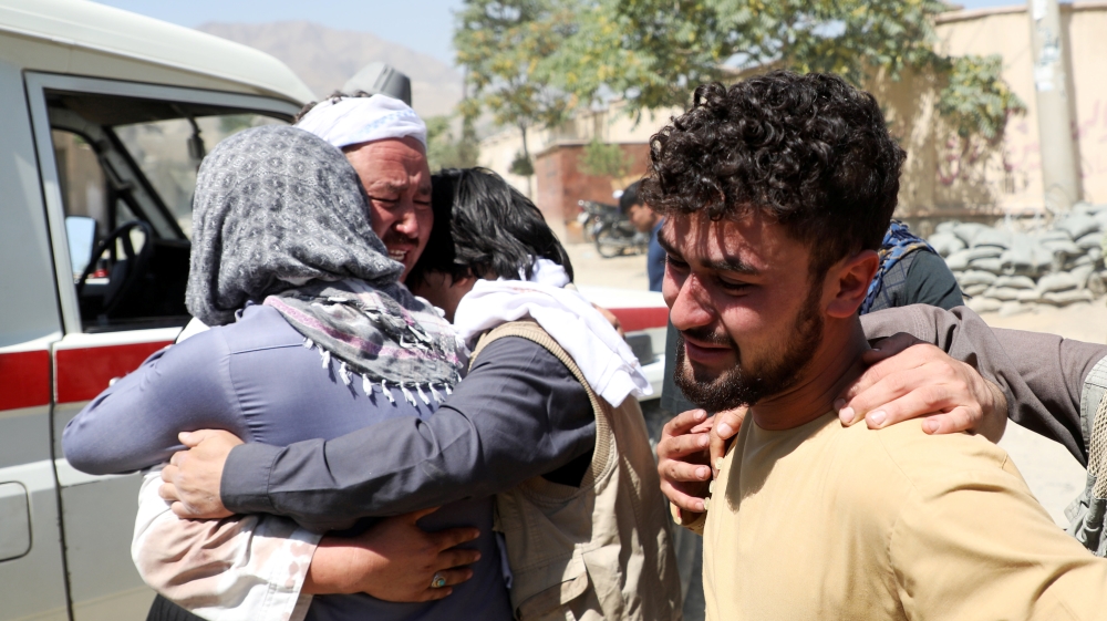 Afghan men comfort each other as they mourn during the funeral of their relatives after a suicide bomb blast at a wedding in Kabul