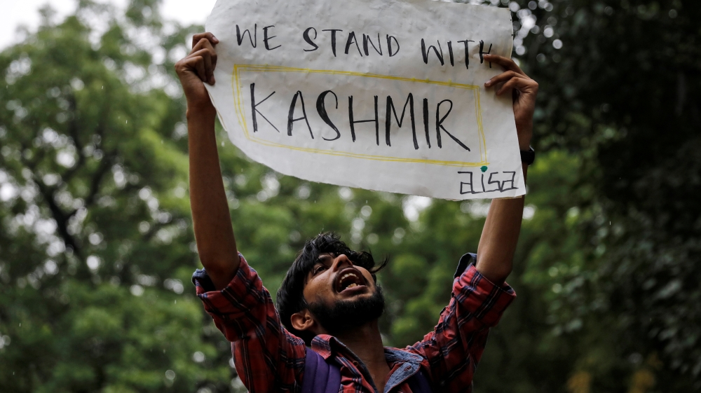 A man holds a sign and shouts slogans during a protest after the government scrapped the special status for Kashmir, in New Delhi