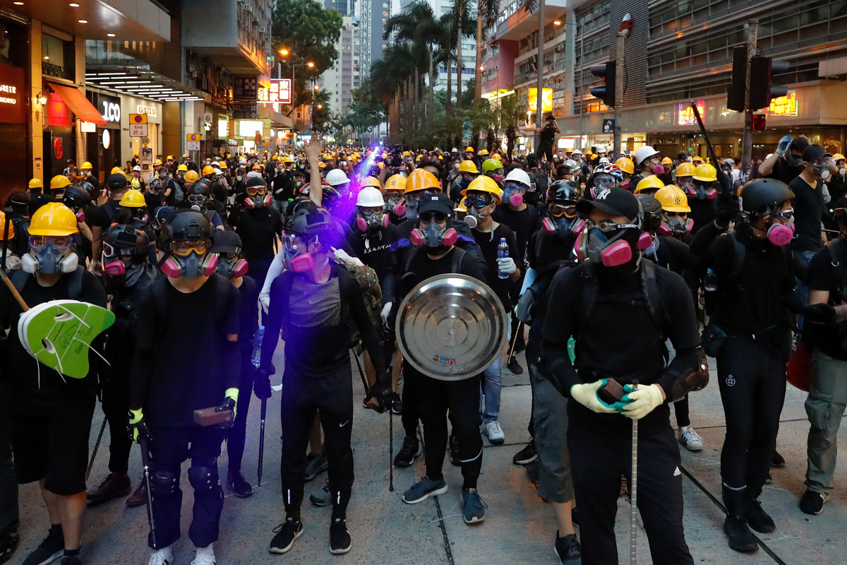 Protesters with protection gears face with riot policemen on a street during the anti-extradition bill protest in Hong Kong, Sunday, Aug. 11, 2019. Police fired tear gas late Sunday afternoon to try t