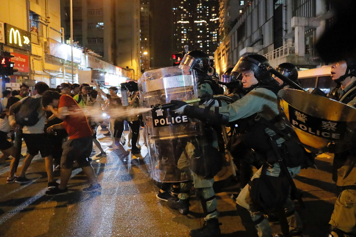 Riot police use pepper spray against protesters during the anti-extradition bill protest in Hong Kong, Sunday, Aug. 11, 2019. Police fired tear gas Sunday inside a train station and in several other H
