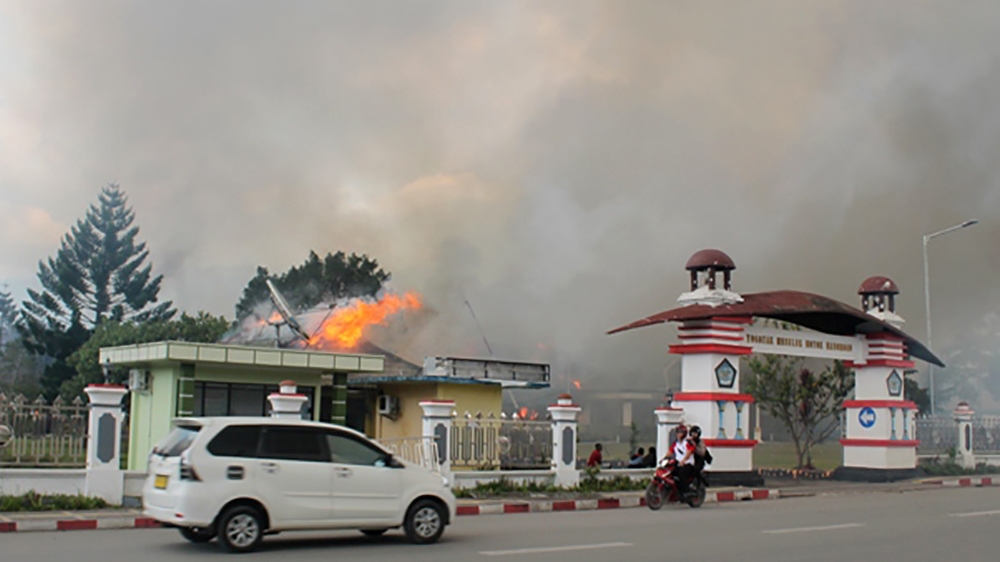 A car passes governor office building of Jayawijaya burned during a protest in Wamena, Papua