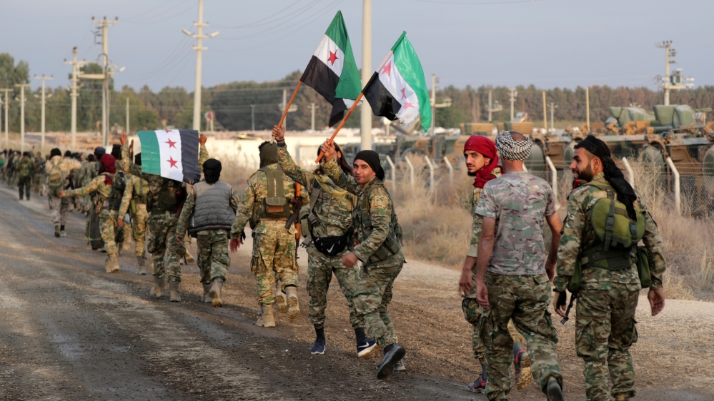 Turkey-backed Syrian rebel fighters hold the Syrian opposition flag as they walk together in the border town of Akcakale in Sanliurfa province