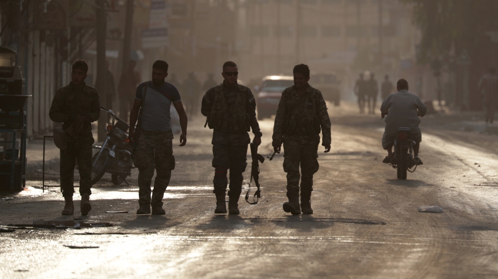 Turkey-backed Syrian rebel fighters walk together in the border town of Tal Abyad, Syria, October 15, 2019