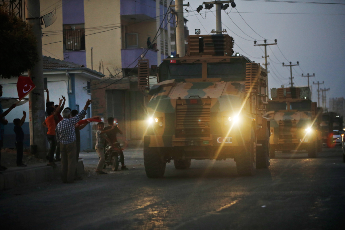 Shortly after the Turkish operation inside Syria had started, local residents cheer and applaud as a convoy of Turkish forces vehicles is driven through the town of Akcakale, Sanliurfa province, south