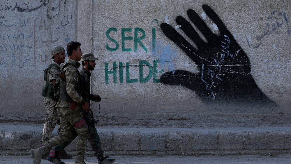 Turkey-backed Syrian rebel fighters walk in the town of Tal Abyad, Syria October 13, 2019