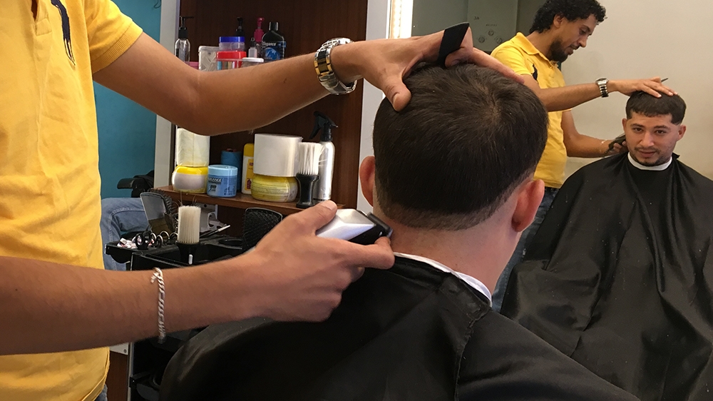 Ashrif gets a haircut at his local barber, like many Tunisians, he says he's lost faith in politicians but trusts Kais Saied [Sofia Barbarani/Al Jazeera]