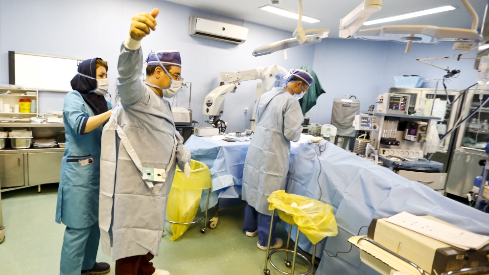 Iranian surgeon Ali Manafi puts on his sterile