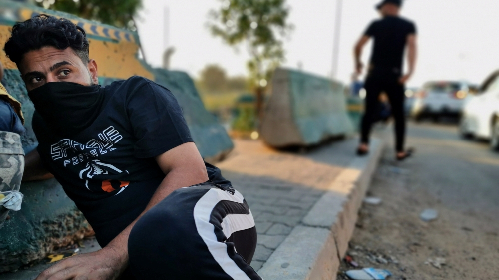 Demonstrators take cover during a protest after the lifting of the curfew, following four days of nationwide anti-government protests that turned violent, in Baghdad, Iraq October 5, 2019.