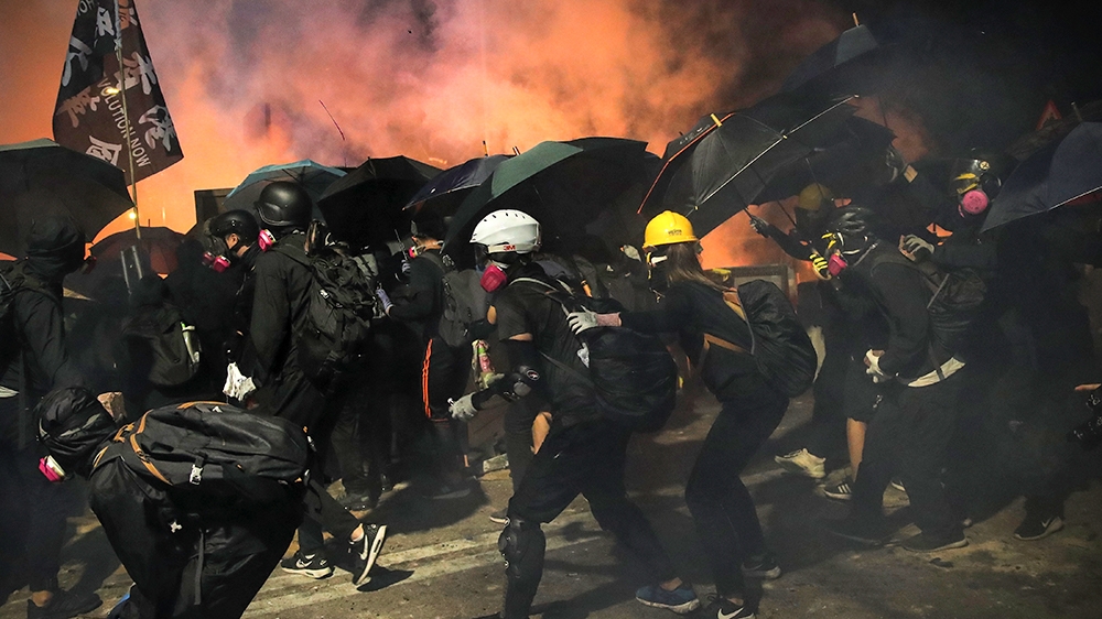 Students use umbrellas as a shield during a clash with police at the Chinese University in Hong Kong, Tuesday, Nov. 12, 2019. Police and protesters battled outside university campuses and several thou