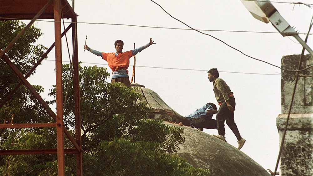 Hindu fundamentalists stand on top of one of the three domes of the Babri mosque in Ayodhya, Sunday, December 06, 1992, after storming the security cordon. Thousands of Hindu extremists razed the 430-