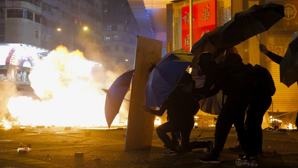 Protesters cover with umbrellas from tear gas canister in the Kowloon area of Hong Kong