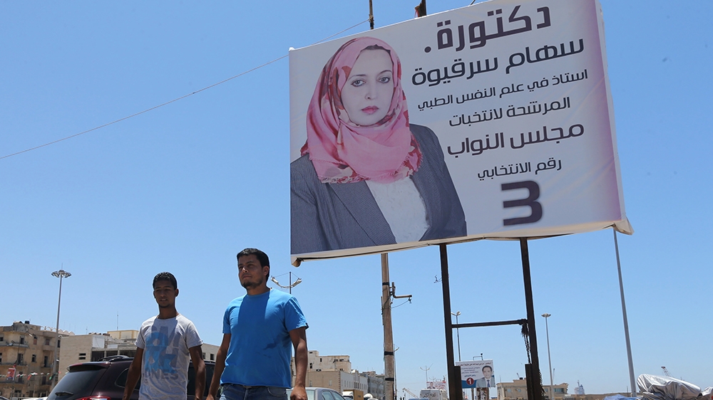 People walk past an election campaign poster for Seham Sergiwa, a candidate vying for a seat in Libya''s House of Representatives, in Benghazi June 16, 2014. Libyan authorities are struggling to restor