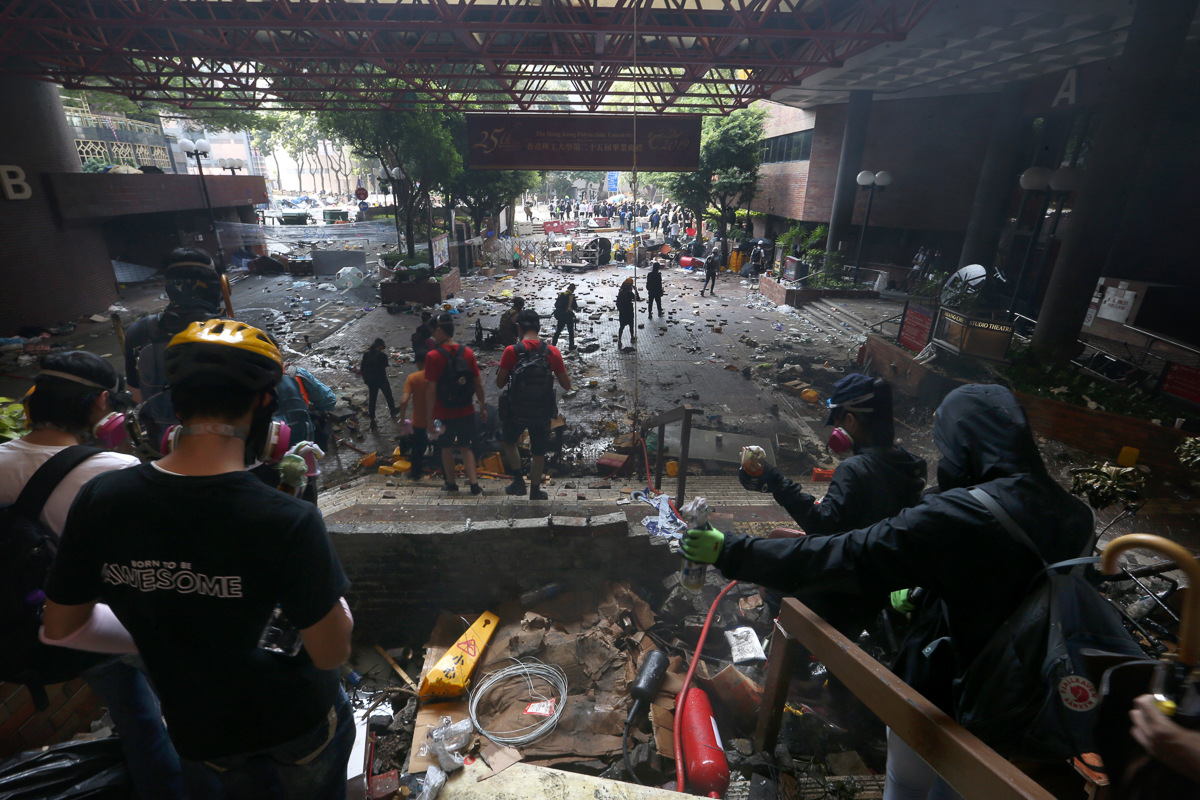 Protesters stand on the steps of Hong Kong Polytechnic University in Hong Kong, Monday, Nov. 18, 2019. Hong Kong police have swooped in with tear gas and batons as protesters who have taken over the u