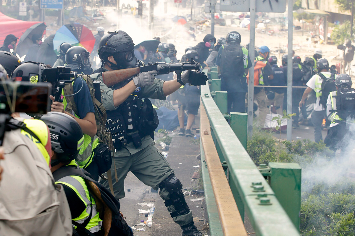 A police officer prepares to fire tear gas canisters during a clash with protestors near the Hong Kong Polytechnic University in Hong Kong, Monday, Nov. 18, 2019. Hong Kong police have swooped in with