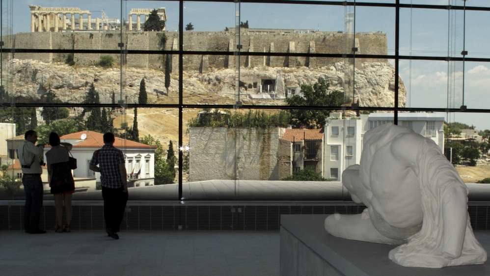 Visitors look at the temple of the Parthenon from inside the new Acropolis museum in Athens