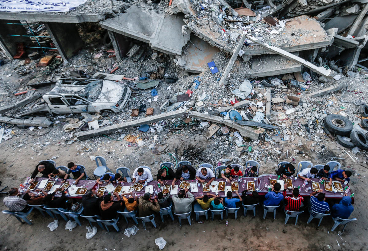 Palestinian families break their fast next to a building destroyed in recent confrontations between Hamas and Israel, in the Gaza Strip on May 18, 2019, during the Muslim holy fasting month of Ramadan
