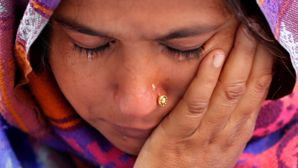 A woman weeps as she waits outside a mortuary to receive the body of her relative who died in a fire that swept through a factory where laborers were sleeping, in New Delhi