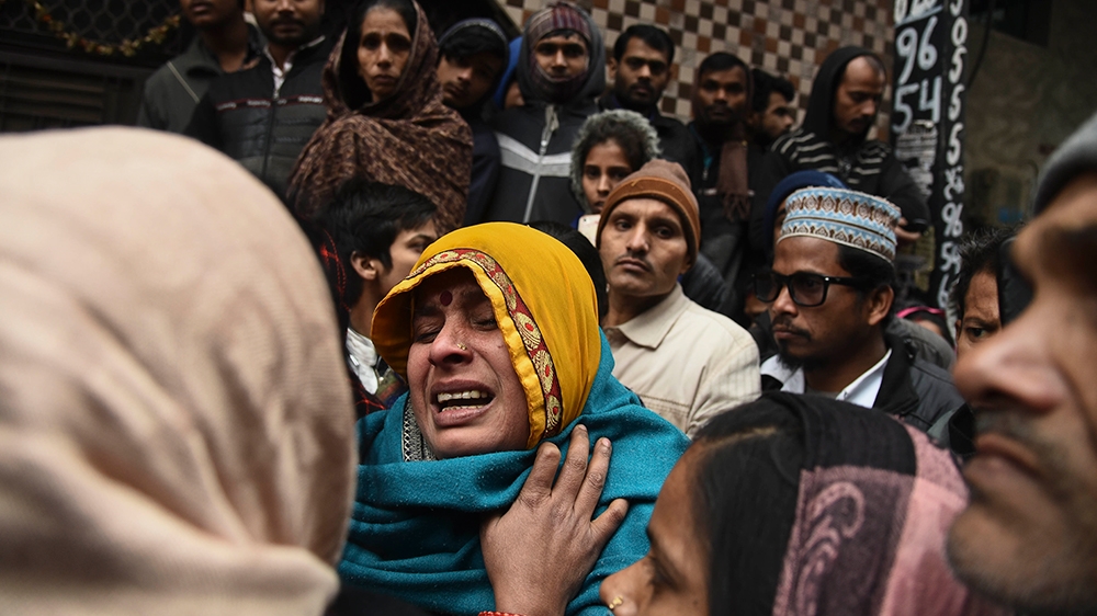 A woman tries to console a wailing relative of a victim as people gather around a warehouse where a fire broke out in the early hours of Monday at Kirari area of New Delhi, India, Monday, Dec.23, 2019