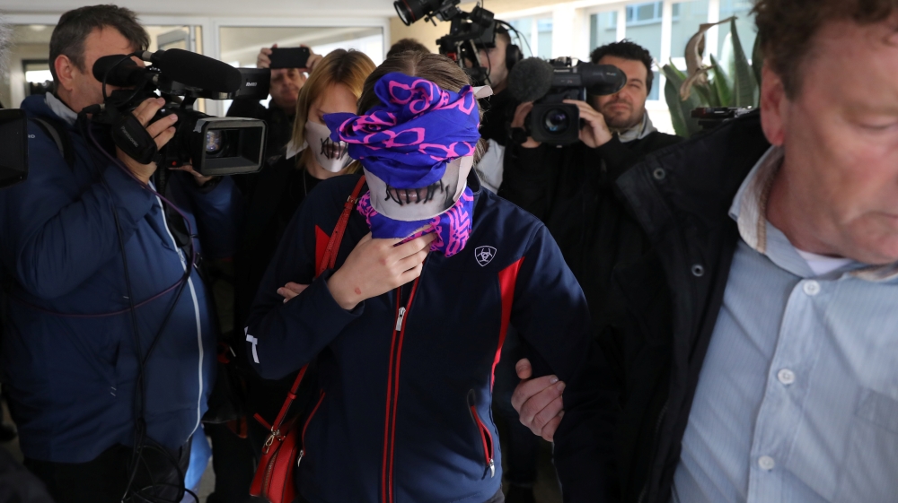 A British woman, accused of lying about being gang raped, covers her face as she leaves Famagusta courthouse in Paralimni