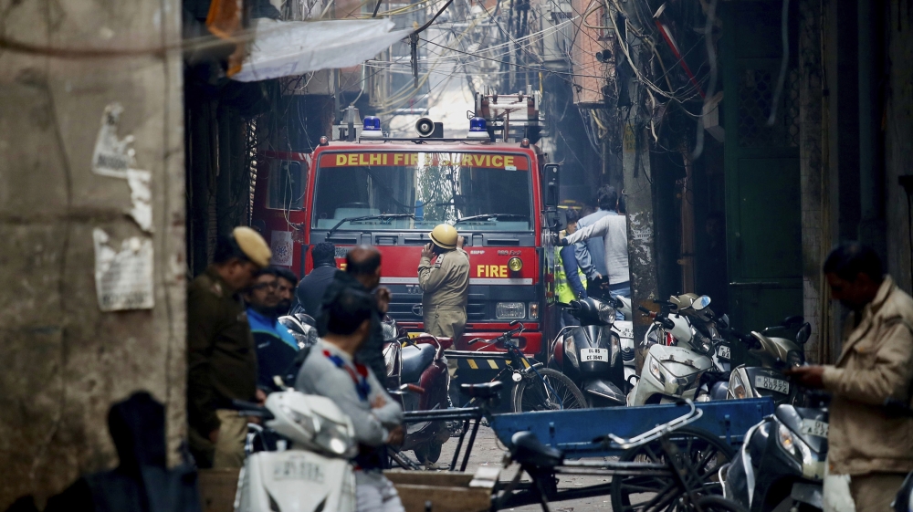 A fire engine stands by the site of a fire in an alleyway, tangled in electrical wire and too narrow for vehicles to access, in New Delhi, India, Sunday, Dec. 8, 2019. Dozens of people died on Sunday