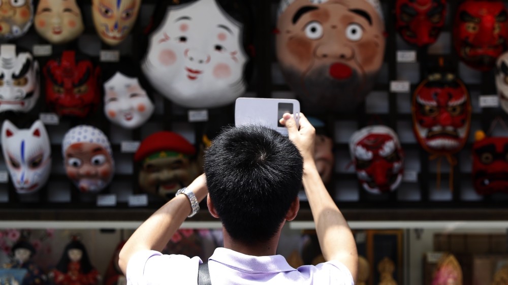 A tourist from China takes pictures of Japanese traditional masks
