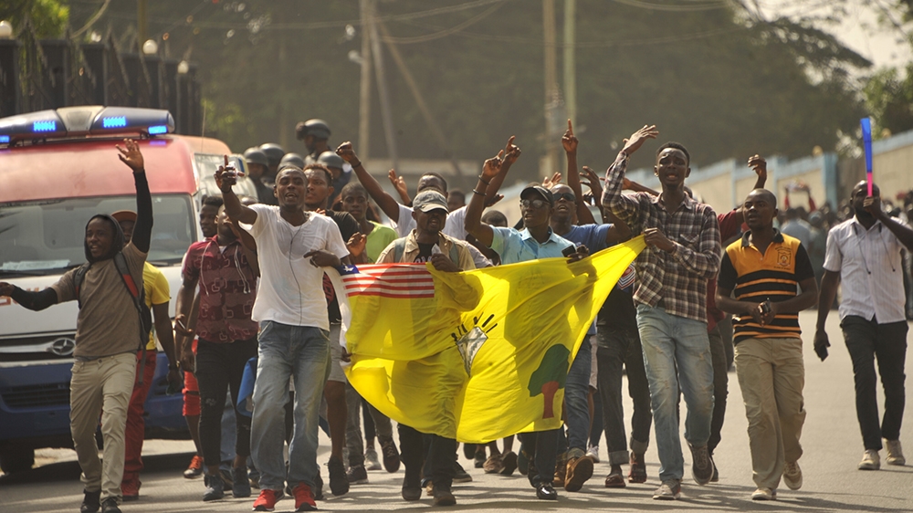 Members of the Council of Patriots (COP) hold a flag as they protest outside Monrovia's Capitol building against the deepening economic crisis under Liberian President George Weah, in Monrovia on Jan