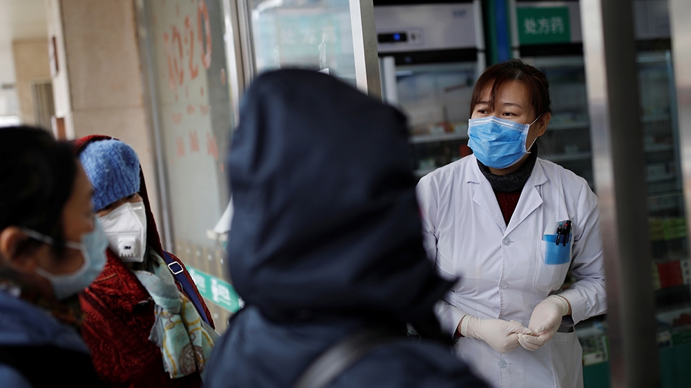 A staff wearing a face mask attends to customers at a pharmacy as the country is hit by an outbreak of the new coronavirus, in Beijing, China February 3, 2020. REUTERS/Carlos Garcia Rawlins
