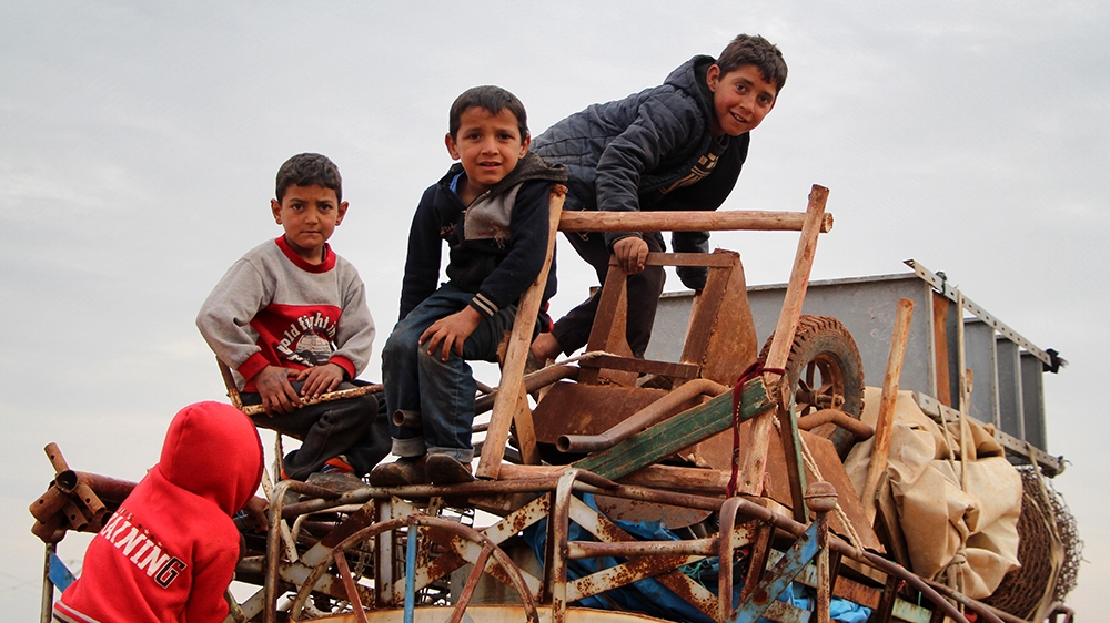 (FILES) In this file photo taken on February 15, 2020 children ride atop a water truck that is also loaded with furniture in the countryside of the village of Saharah, lying on the western edge of Syr