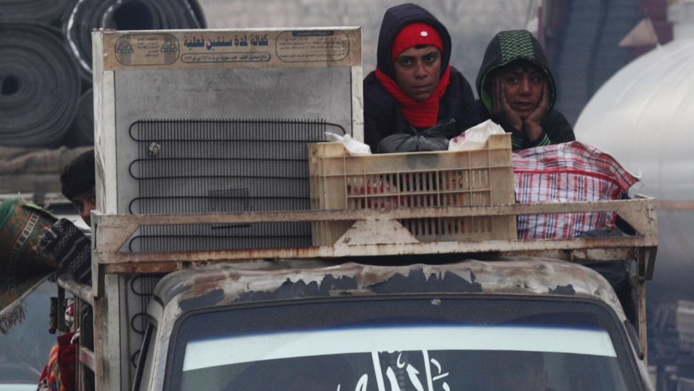 Displaced Syrian boys ride on a truck with belongings in northern Idlib