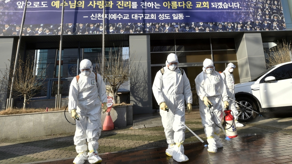 Health officials in Daegu spray disinfectant in front of a church
