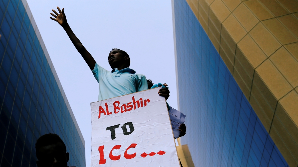A protester holds a placard during a rally calling for a stop to killing in Darfur and stability for peace, next to a building in front of Ministry of Justice in Khartoum