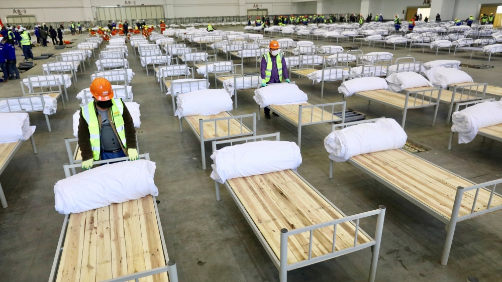 Workers set up beds at the Wuhan Parlor Convention Center on Tuesday to convert it into a makeshift hospital [China Daily via Reuters]