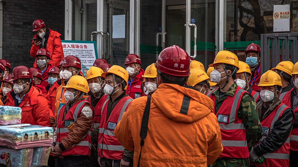 epa08202429 Construction workers wearing protective face masks stand on a street in Beijing, China, 08 February 2020. The novel coronavirus (2019-nCoV), which originated in the Chinese city of Wuhan,