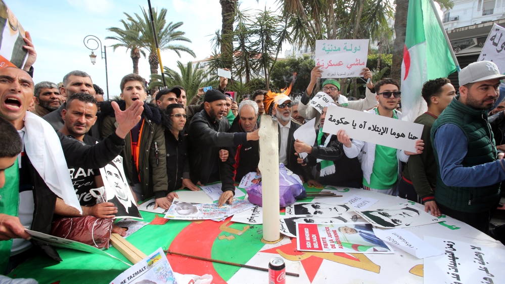 Demonstrators gather around a candle to mark the first anniversary of protests in Algiers