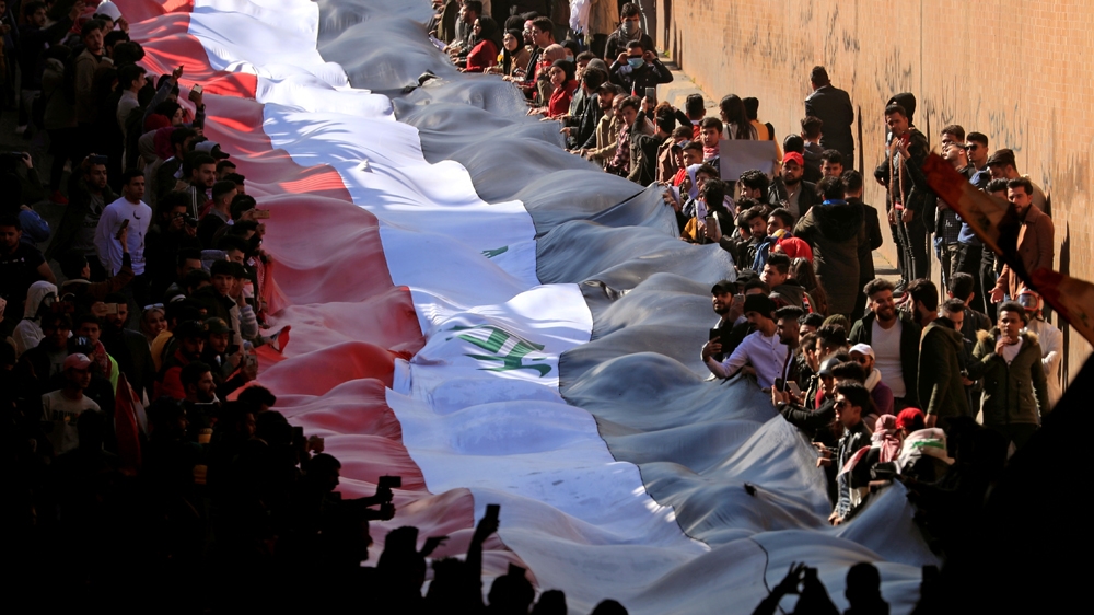 University students carry Iraqi flag to express their rejection of the newly appointed Prime Minister of Iraq, Mohammed Tawfiq Allawi, during ongoing anti-government protests in Baghdad, I