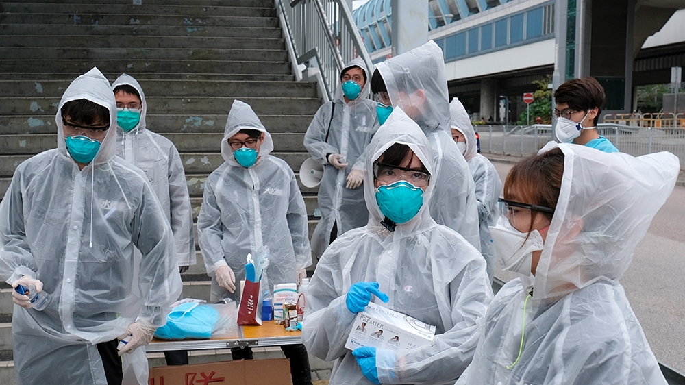 Residents wearing masks and raincoats volunteer to take temperature of passengers following the outbreak of a new coronavirus at a bus stop at Tin Shui Wai, a border town in Hong Kong, China February