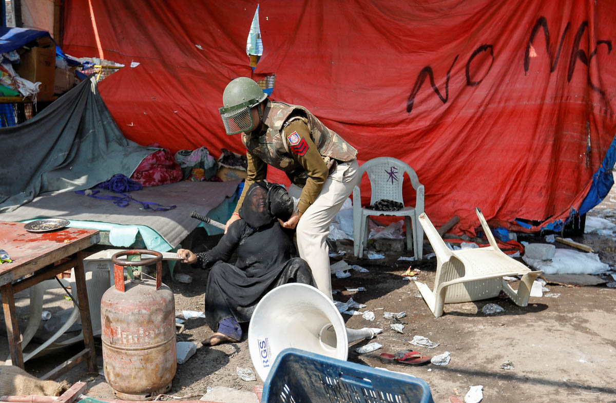 A woman opposing a new citizenship law is helped by a policeman after she was beaten by people supporting the law, at a protest site in New Delhi, India, February 24, 2020. REUTERS/Danish Siddiqui