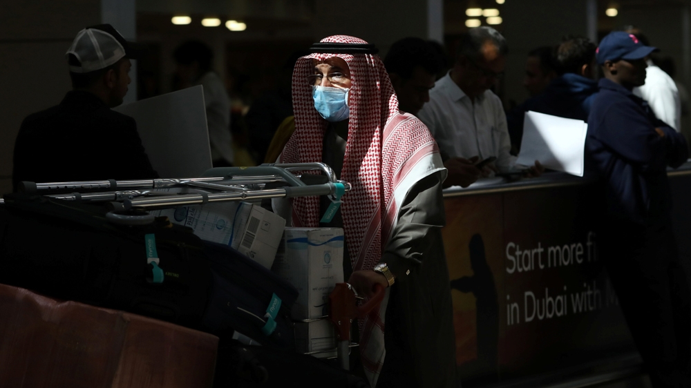 A traveller wears a mask as he pushes a cart with luggage at the Dubai International Airport, after the UAE's Ministry of Health and Community Prevention confirmed the country's first case 