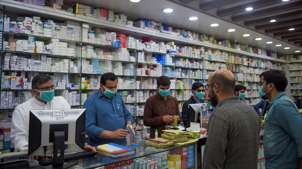 Pharmacy employees wearing facemasks as a preventive measure against the COVID-19 coronavirus attend to customers in Islamabad on March 23, 2020. Farooq NAEEM / AFP